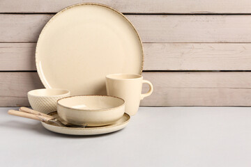 Set of different dishes on table near white wooden wall