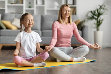 Fototapeta na wymiar Family Yoga. Mother And Little Daughter Meditating Together At Home