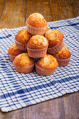 A Pile of Cupcakes on a Wooden Background and a Kitchen Rag