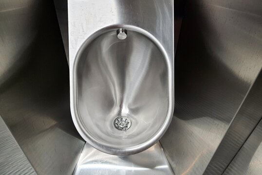 Sanitary metal urinal, toilet bowl in public bathroom with hygienic automatic water saving electronic flush. Urinal with urine sensor. Inductive flush toilet. WC