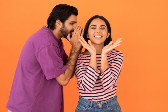 Indian guy sharing secrets with his emotional pretty girlfriend