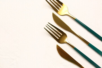 Golden forks and knives with green handles on white background