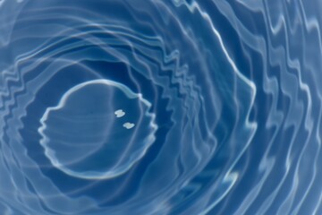 Blue water with ripples on the surface. Defocus blurred transparent blue colored clear calm water surface texture with splashes and bubbles. Water waves with shining pattern texture background.
