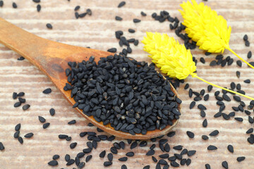 Black cumin seeds and essential oil with bowl and wooden shovel or spoon. Nigella Sativa in glass bottle. Organic herbal medicine for many diseases