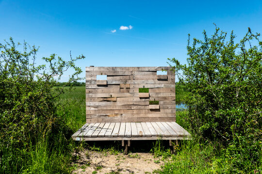 A wooden wall with openings for photographers to photograph exotic birds in the marshes