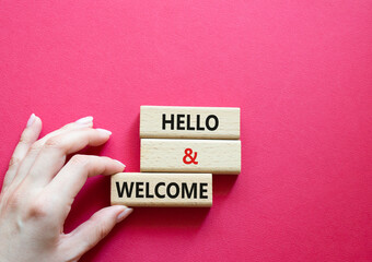 Hello and Welcome symbol. Concept words Hello and Welcome on wooden blocks. Beautiful red background. Businessman hand. Business and Hello and Welcome concept. Copy space.