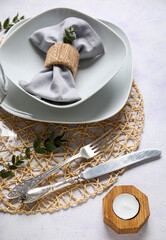 Wicker mat with stylish table setting and candle on grunge white background