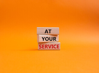 At your service symbol. Wooden blocks with words At your service. Beautiful orange background....