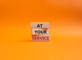 At your service symbol. Wooden blocks with words At your service. Beautiful orange background. Business and At your service concept. Copy space.