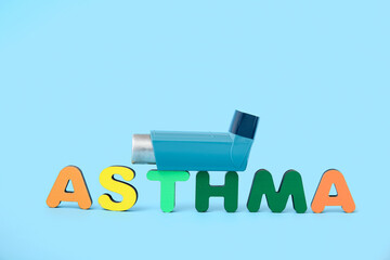 Word ASTHMA and inhaler on blue background