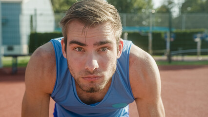 Focused young professional male Caucasian athlete ready for the run race in a sprint starting position