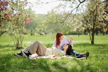 Beautiful two ladies lesbian laying down on the grass in the middle of the park hugging each other and fed in love