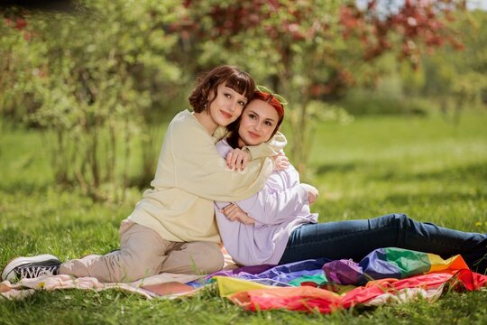 In a sunny day lesbian couple very charismatic laying down on the grass and looking over the digital tablet concept of lgbt lifestyle