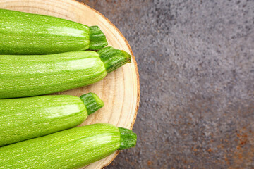 Board with fresh green zucchini on dark background