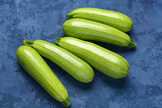 Many fresh green zucchini on blue background