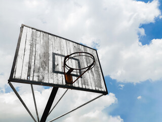 Photograph of Basketball backboard with traces of wear, sport theme, blue sky with clouds
