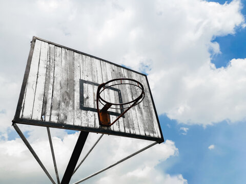 Photograph of Basketball backboard with traces of wear, sport theme, blue sky with clouds