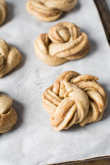 Swedish cinnamon buns dough on a parchment lined baking pan, unbaked cinnamon twists, process of making Kanelbullar