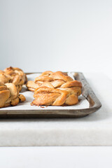 Swedish cinnamon buns on a parchment lined baking sheet, cinnamon twists on a baking tray, homemade Kanelbullar on a cookie sheet