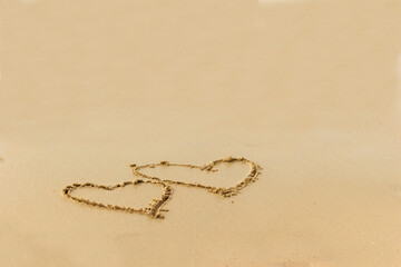 Hearts drawn on the wet sand on the beach. Concept of love; romance; feelings.