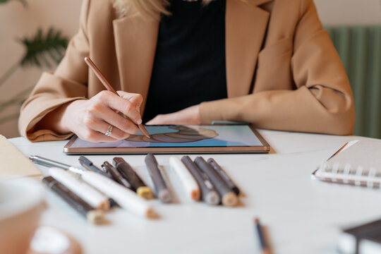 Close-up of an Illustrator sitting at a table drawing a donut on a digital tablet