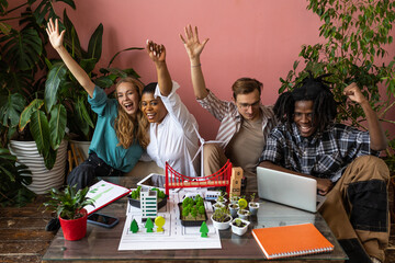 International group of students working on modern urban architecture project with renewable green energy source, alternative electricity, waste recycling. Excited and happy to win ecology contest