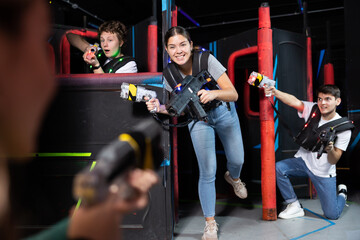 Three people having fun playing lasertag in arena