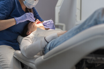 Fototapeta premium The dentist cleans the patient's mouth.