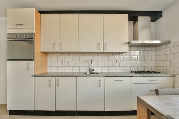 a kitchen with white cabinets and black counter tops on the island in front of the sink is an oven,...