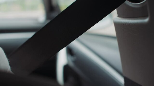 Close-up of a hand reaching for a seatbelt in a car