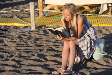 Blonde Woman Reading a Book On The Beach