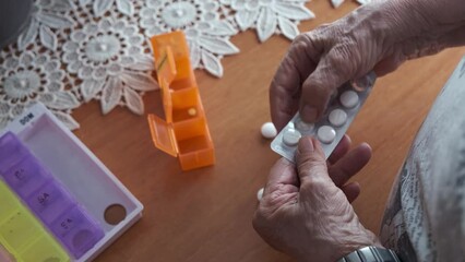 hands of an elderly person, prepare and order the pillbox with the medication for the treatment of the week for a sick person
