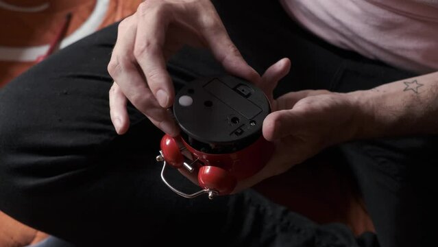 hands of relaxed man assembling a broken alarm clock with a screwdriver , he checks that it works correctly
