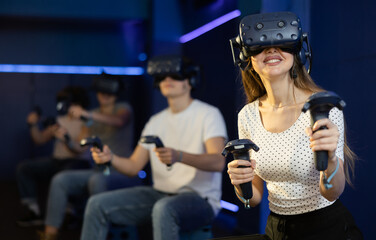 Girl is enjoying exciting movie with friends in VR glasses in entertainment room