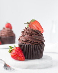 Chocolate cupcake with dark chocolate buttercream and strawberries, double chocolate cupcakes with american buttercream, tall swirl frosting on a cupcake with a strawberry