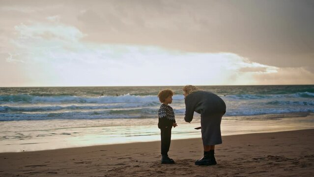 Parent scolding little boy on beach. Young mother talking boy resting shore