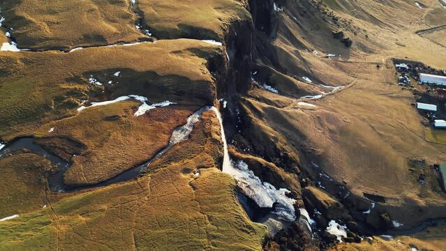 River course flowing among hills in iceland, natural foss a sidu waterfall in icelandic scenery. Spectacular cascade falling off from scandinavian cliffs. Slow motion. Drone shot.
