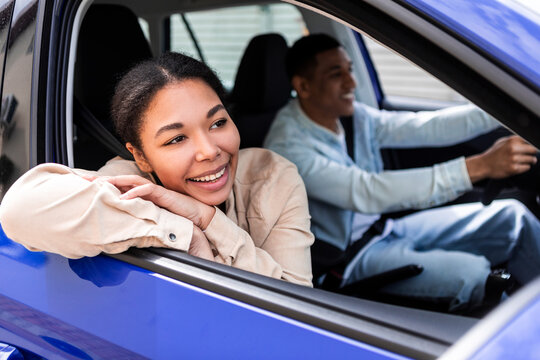 Smiling African American Couple Driving Car Enjoying First Ride Together, Woman Sitting In Front Passenger's Seat Looking Through Opened Window