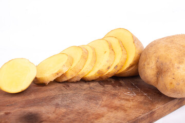 Potatoes are cut into pieces on a wooden cutting board