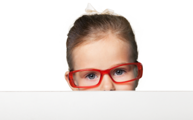 Girl in red-framed eyeglasses looking up from behind the table