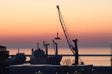 Fototapeta premium Sunrise at the pier with a crane silhouette