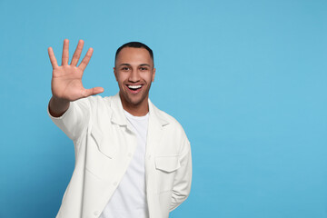 Man giving high five on light blue background. Space for text