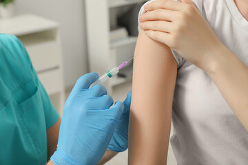 Doctor giving hepatitis vaccine to patient in clinic, closeup