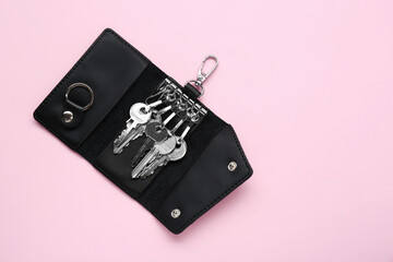 Leather ring holder with keys on pink background, top view. Space for text