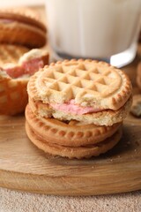 Tasty sandwich cookies with cream on wooden board, closeup