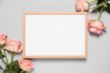 Empty photo frame and beautiful flowers on light background, flat lay. Space for design