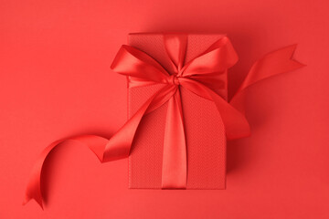 Beautiful gift box with bow on red background, top view