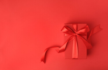 Beautiful gift box with bow on red background, top view. Space for text