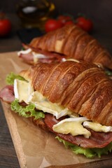 Tasty croissant with brie cheese and bacon on table, closeup