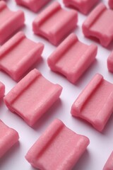 Tasty pink chewing gums on white background, closeup